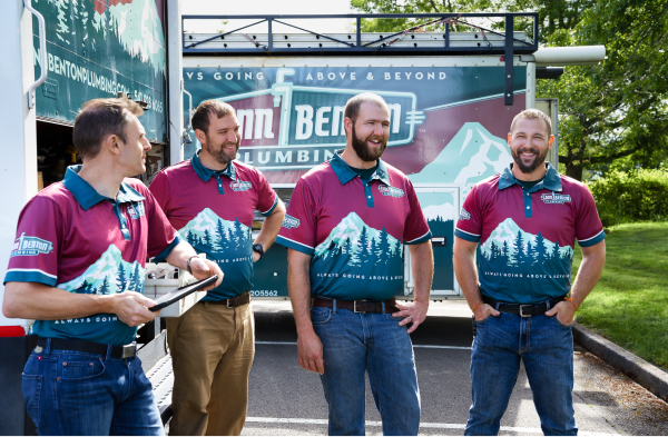four men standing by some work trucks smiling